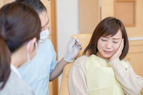 歯医者で歯の痛みを歯科医師に訴える患者