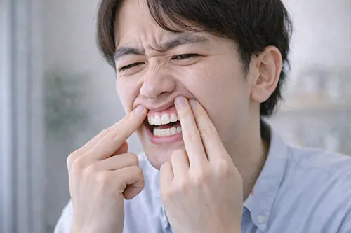 手鏡で口元を見て落ち込む人