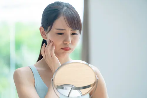 コンプレックスの口元を鏡で見る女性