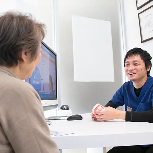 高齢者がインプラント治療について歯科医師に相談しているイメージ