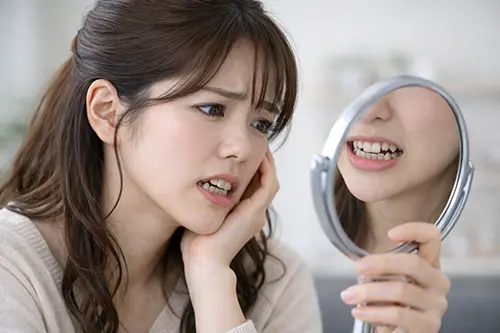 手鏡で口元を見て落ち込む人