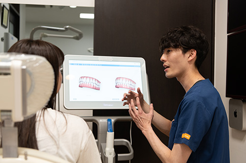 歯並びについて患者に説明する歯科医師