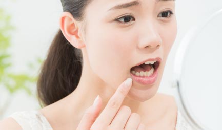 鏡で口の中を見る女性